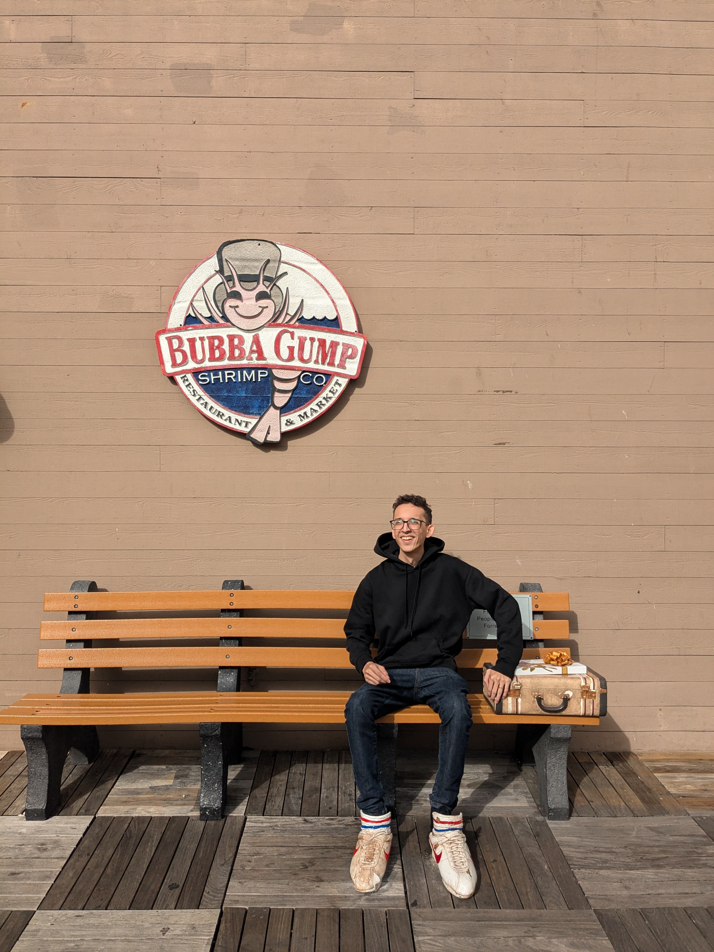 White Mediterranean-style house with a terracotta roof, surrounded by lush greenery and partially obscured by vibrant red-orange flowers in the foreground